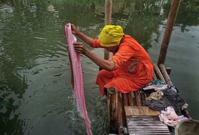 Rear view of man holding umbrella on lake