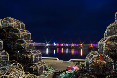 Illuminated bridge over sea against sky at night