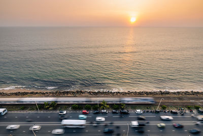 Road and railway track along coast at sunset over ocean. train arriving in colombo, sri lanka.