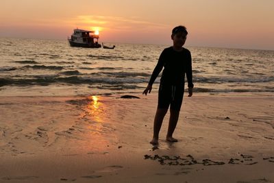 Man standing on beach against sky during sunset