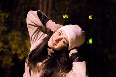 Portrait of smiling young woman wearing knit hat at night