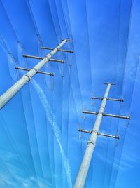 Low angle view of electricity pylon against blue sky