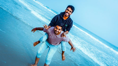 Full length of young couple kissing against blue sea