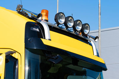 Front view to headlights and a sound signal on the roof of a yellow cabin truck. closeup.