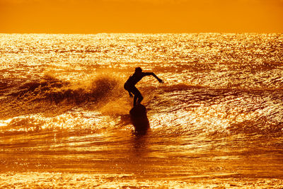 Silhouette man on beach against sky during sunset