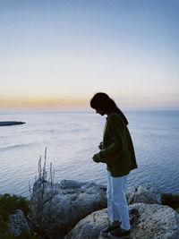 Rear view of man standing against sea during sunset