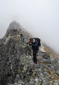 Photographer on rocky mountain in foggy weather
