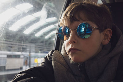 Close-up of boy wearing sunglasses while looking through train window