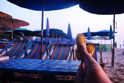 Low section of woman relaxing on table at beach