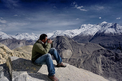 View of man photographing mountain range against sky