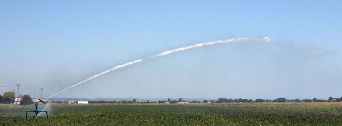 Panoramic view of agricultural sprinkler on farm against clear sky