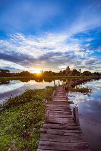 Footpath by lake against sky