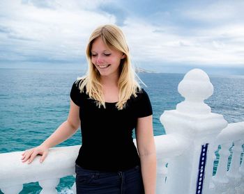 Beautiful young woman standing against sea