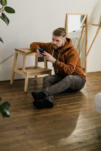 Side view of woman sitting on hardwood floor