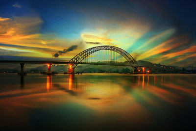 Arch bridge over river against sky during sunset