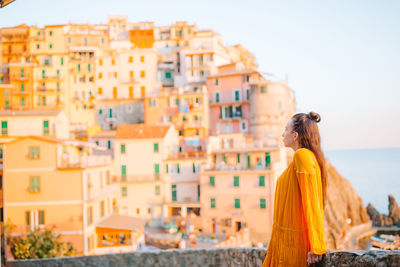 Rear view of woman looking at buildings against sky