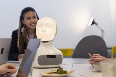 Business people discussing robot voice assistant during meeting