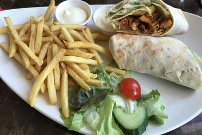 Close-up of french  fries with vegetables served in plate on table