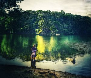 Reflection of woman in lake against trees