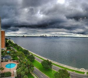 Panoramic view of city by sea against storm clouds