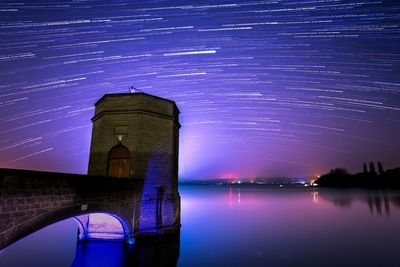 Illuminated tower against star trails at night