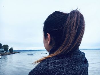 Rear view of woman standing at beach against sky