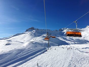 Ski lift over snowcapped mountains against sky