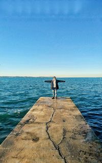 Rear view of woman standing in sea against sky