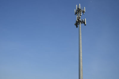 Low angle view of communications tower against clear blue sky