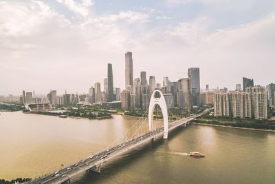 Bridge over river amidst in city against sky