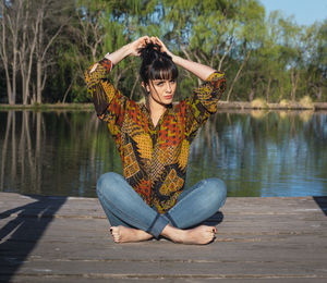 Portrait of young woman sitting by lake