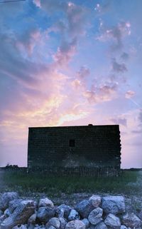 Abandoned house on field against sky during sunset