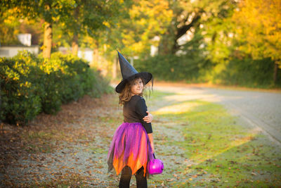 Full length of girl standing by tree