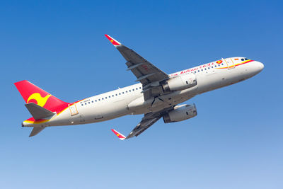 Low angle view of airplane flying against clear blue sky