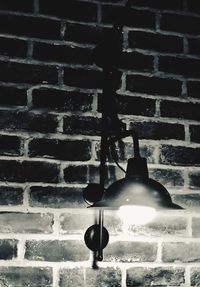 Low angle view of illuminated light bulb against brick wall