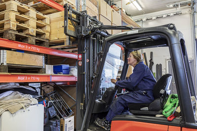 Woman driving forklift truck in warehouse