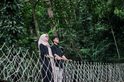 Couple standing by trees in forest