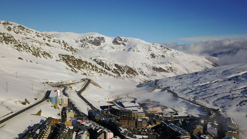 Scenic view of ski resort with snowcapped mountains against clear sky 