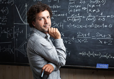 Portrait of teacher standing by blackboard