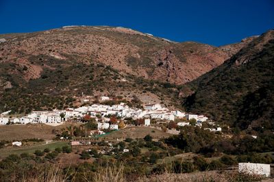 High angle view of houses and mountains against clear blue sky