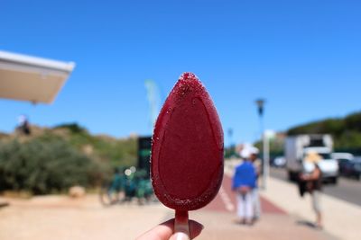 Cropped hand holding popsicle against blue sky