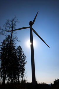 Low angle view of silhouette windmill on field against sky