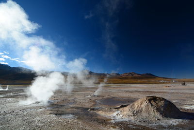 Smoke emitting from volcanic landscape against sky