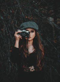 Portrait of young woman wearing hat standing outdoors