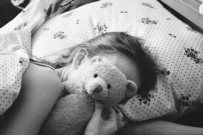 High angle view of girl sleeping with teddy bear on bed at home