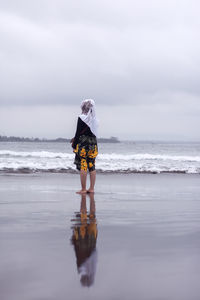 Rear view full length of woman standing on shore at beach