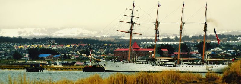 Sailboats moored at harbor against sky