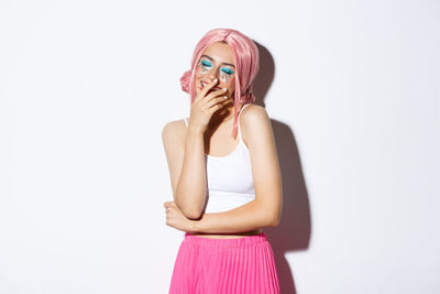 Woman standing against pink background