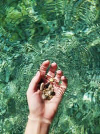 Close-up of hand holding stones above the sea