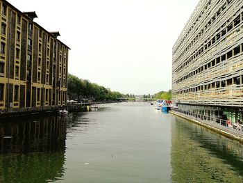 Bridge over river amidst buildings in city against clear sky